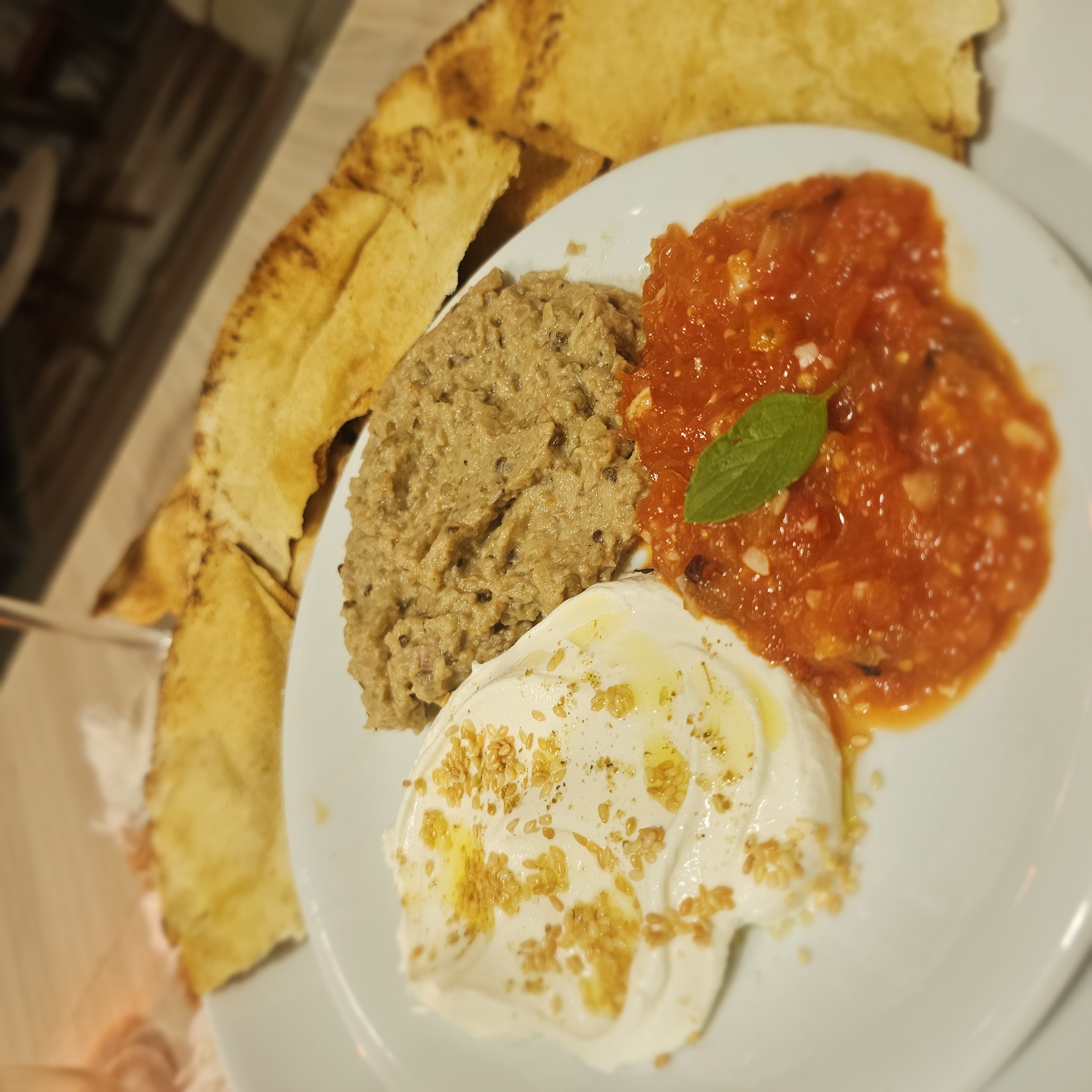 Trio de patês servido em um prato com pão pita.