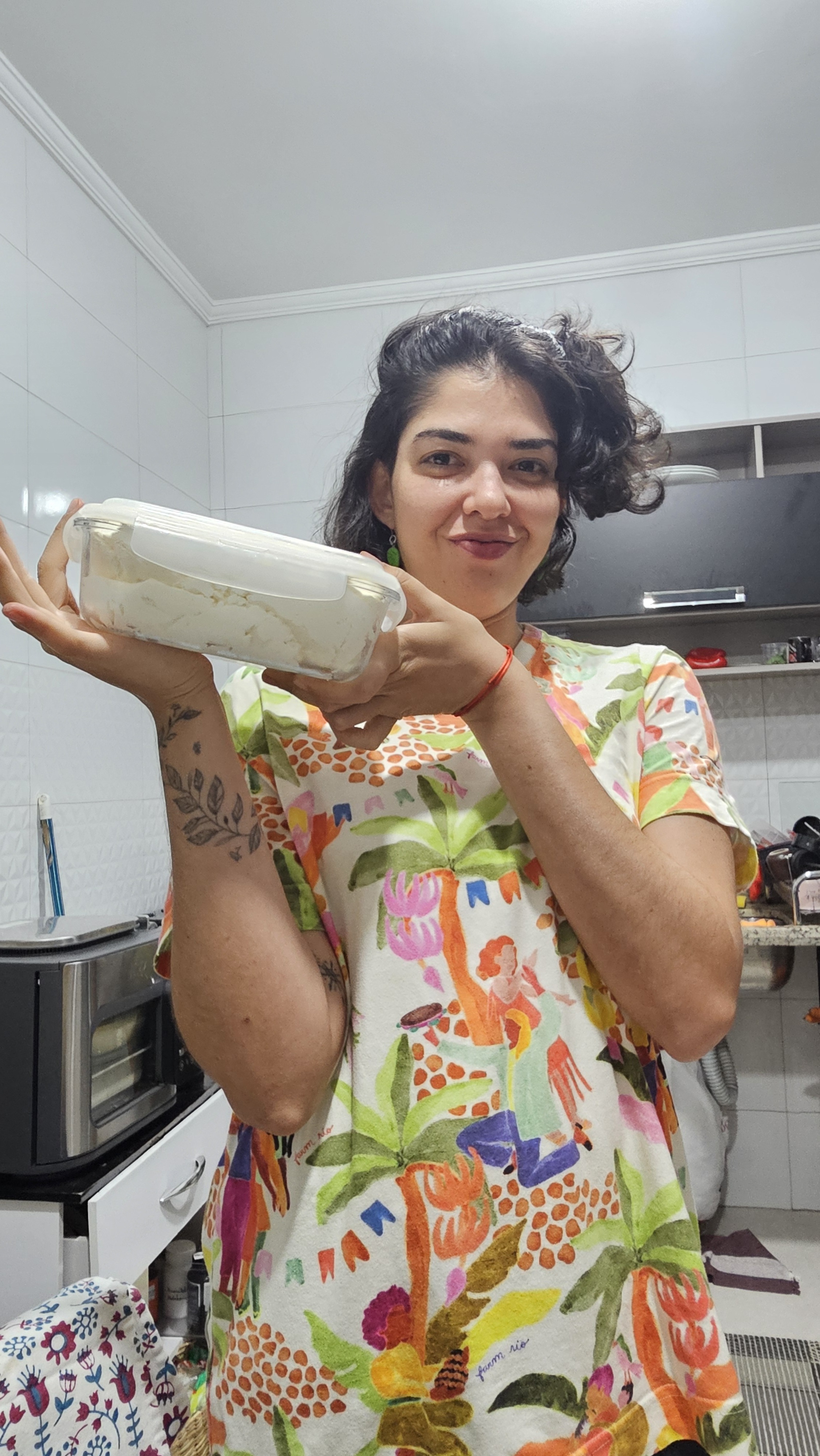 Rafa na cozinha segurando um pote preparado por ela.